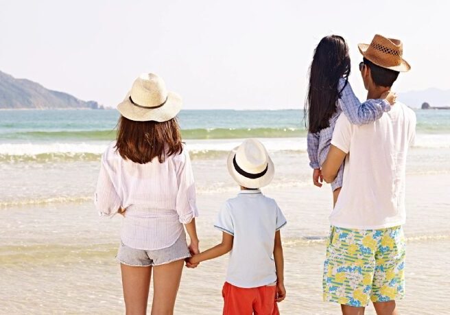 A family standing on the beach holding hands.